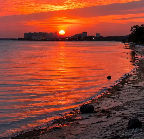 The sun setting over still water, the sky orange and red